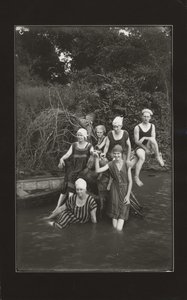 Group of One Man and Four Women in Swimming Suits Seated on a River Bank